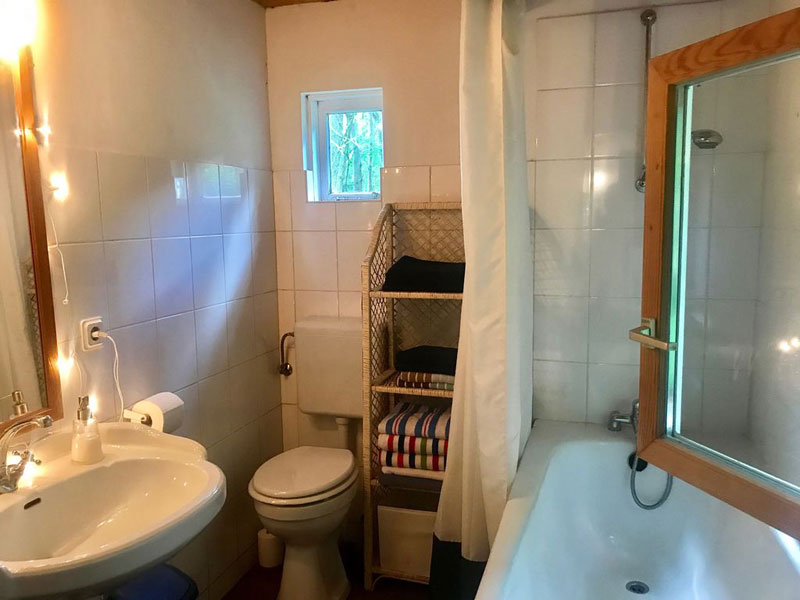 Badezimmer mit Badewanne und Blick in den Wald